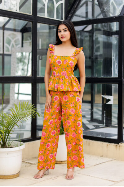 Model wearing Bolbo Sunshine Bloom yellow floral coord set featuring ruffle straps, peplum-style top, and wide-leg pants – front view.