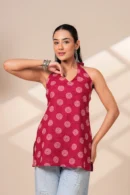 Woman wearing a maroon printed halter neck sleeveless cotton top paired with light blue jeans.